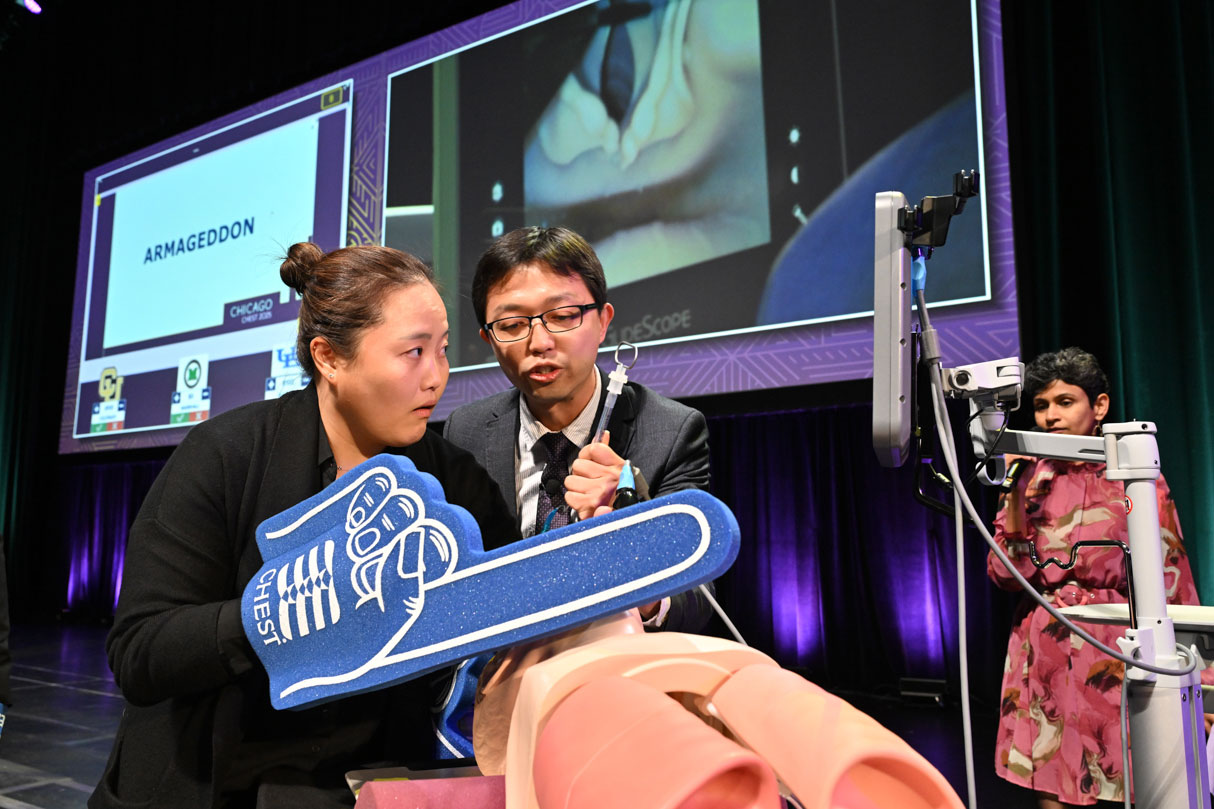 University at Buffalo fellows Jessica Baek, MD, and Yu-Che Lee, MD, MPH, perform an intubation using only their nondominant hands during a minigame at the 2025 CHEST Challenge Championship.